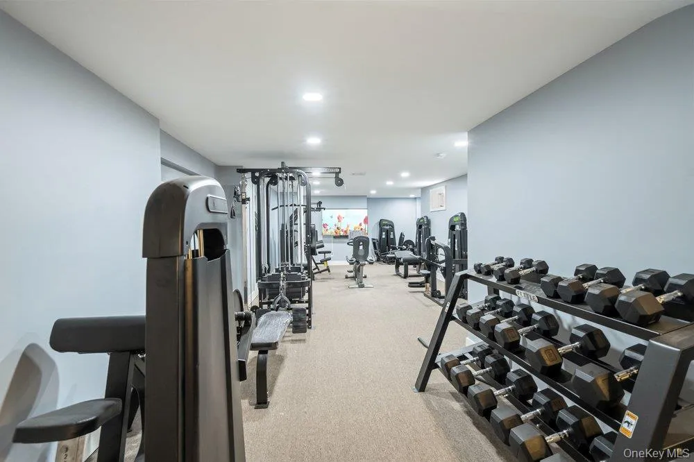 Dedicated fitness area with specialized equipment, integrated lighting, soft carpet flooring, and neutral wall finishes Dedicated fitness area with specialized equipment, integrated lighting, soft carpet flooring, and neutral wall finishes