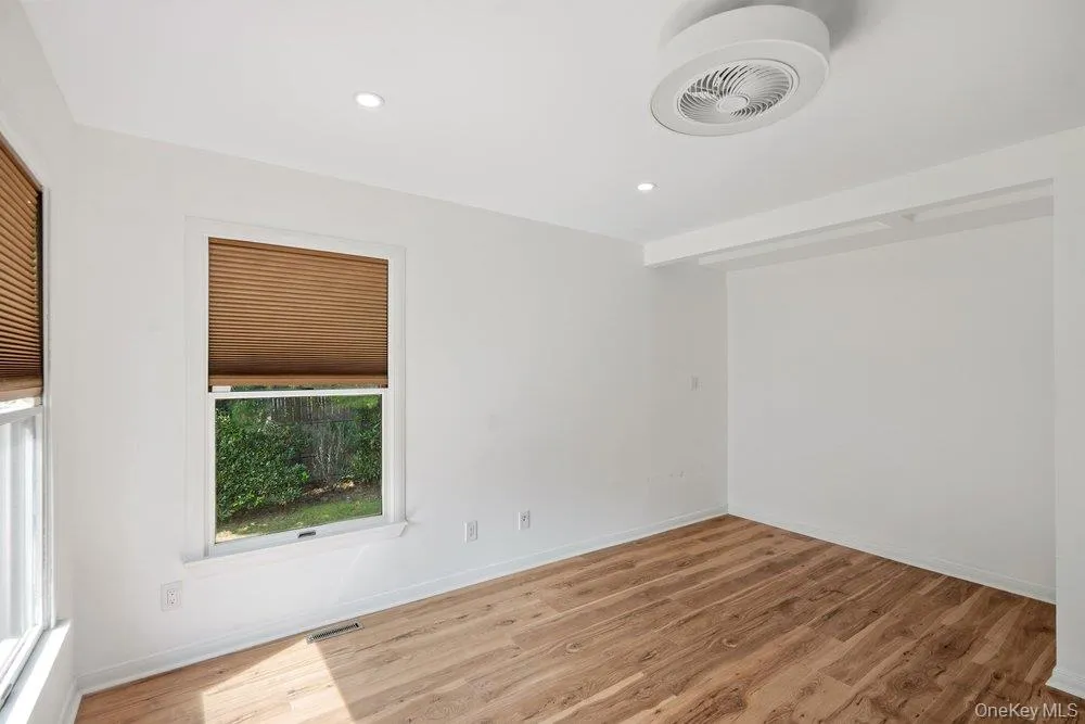 Wood-finish flooring, recessed lighting, white walls, and a contemporary ceiling fan Wood-finish flooring, recessed lighting, white walls, and a contemporary ceiling fan