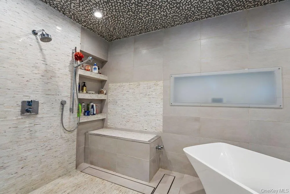 Tiled shower with a built-in bench, integrated shelving, and a dual-head shower system Tiled shower with a built-in bench, integrated shelving, and a dual-head shower system