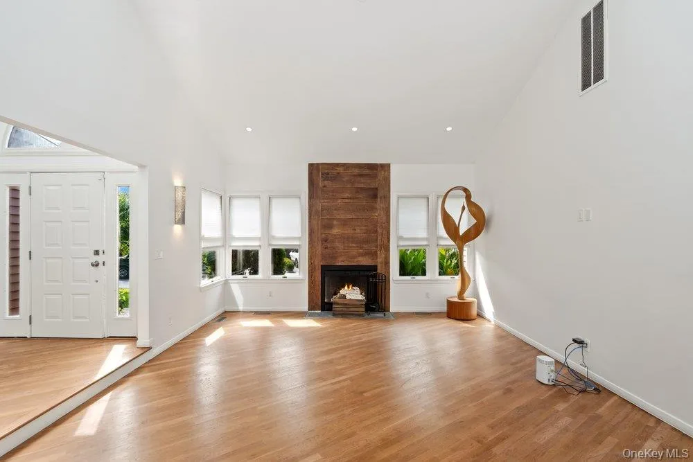 Vaulted ceiling with recessed lighting, wood-finish flooring, wood-paneled fireplace, multi-pane windows, and a double entry door with sidelights Vaulted ceiling with recessed lighting, wood-finish flooring, wood-paneled fireplace, multi-pane windows, and a double entry door with sidelights
