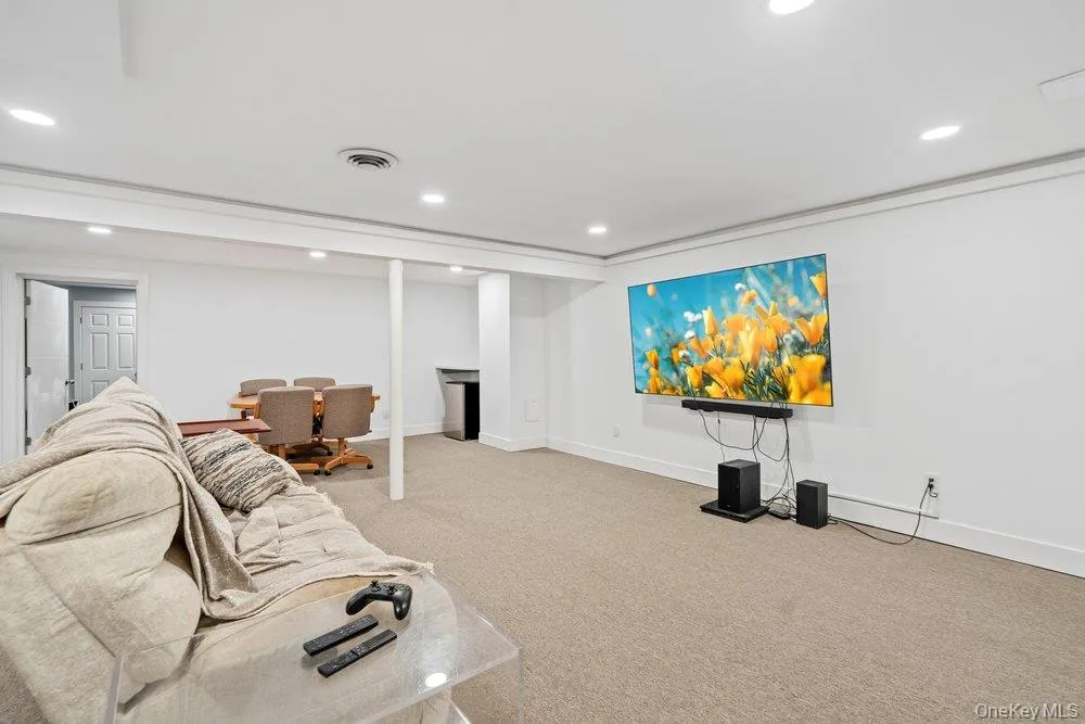 Spacious room featuring neutral carpet flooring, recessed lighting, and a wall-mounted display area Spacious room featuring neutral carpet flooring, recessed lighting, and a wall-mounted display area