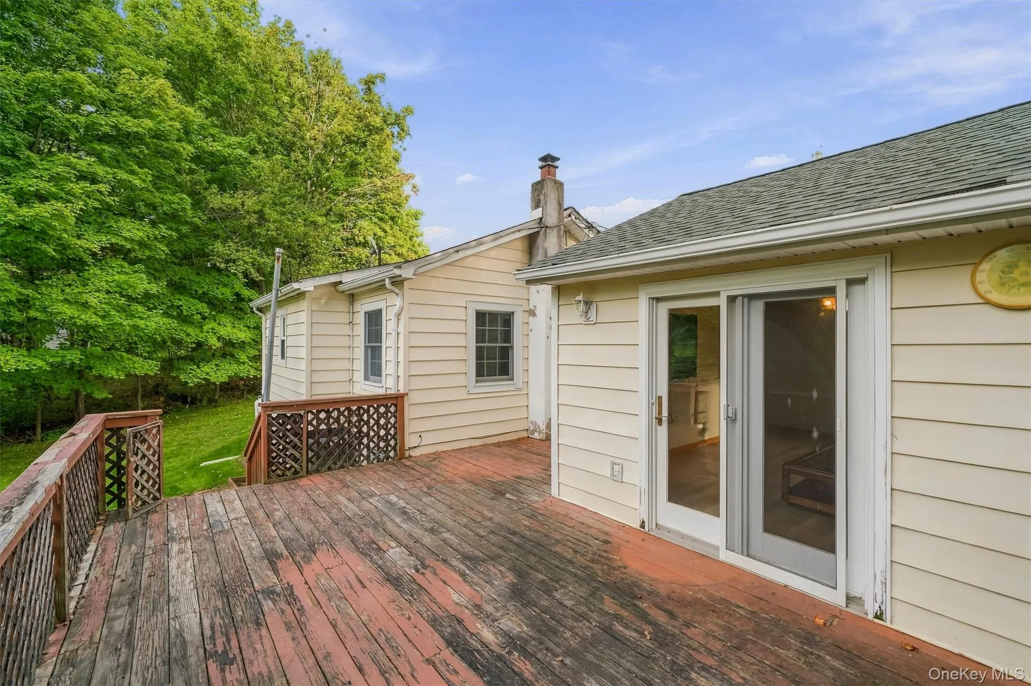 Wood deck with lattice railing, vinyl siding, and sliding glass door Wood deck with lattice railing, vinyl siding, and sliding glass door