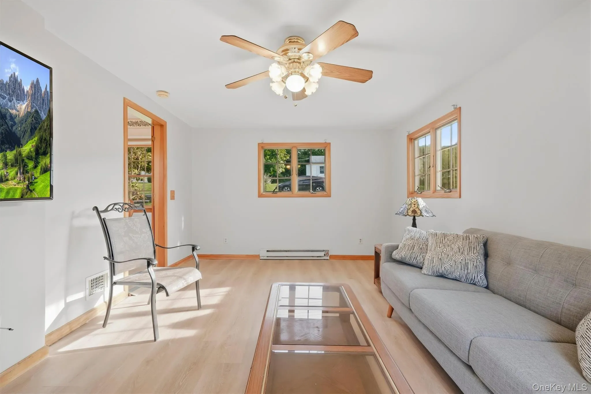 Wood-finish flooring, natural wood trim, ceiling fan with integrated lighting, and multiple windows Wood-finish flooring, natural wood trim, ceiling fan with integrated lighting, and multiple windows