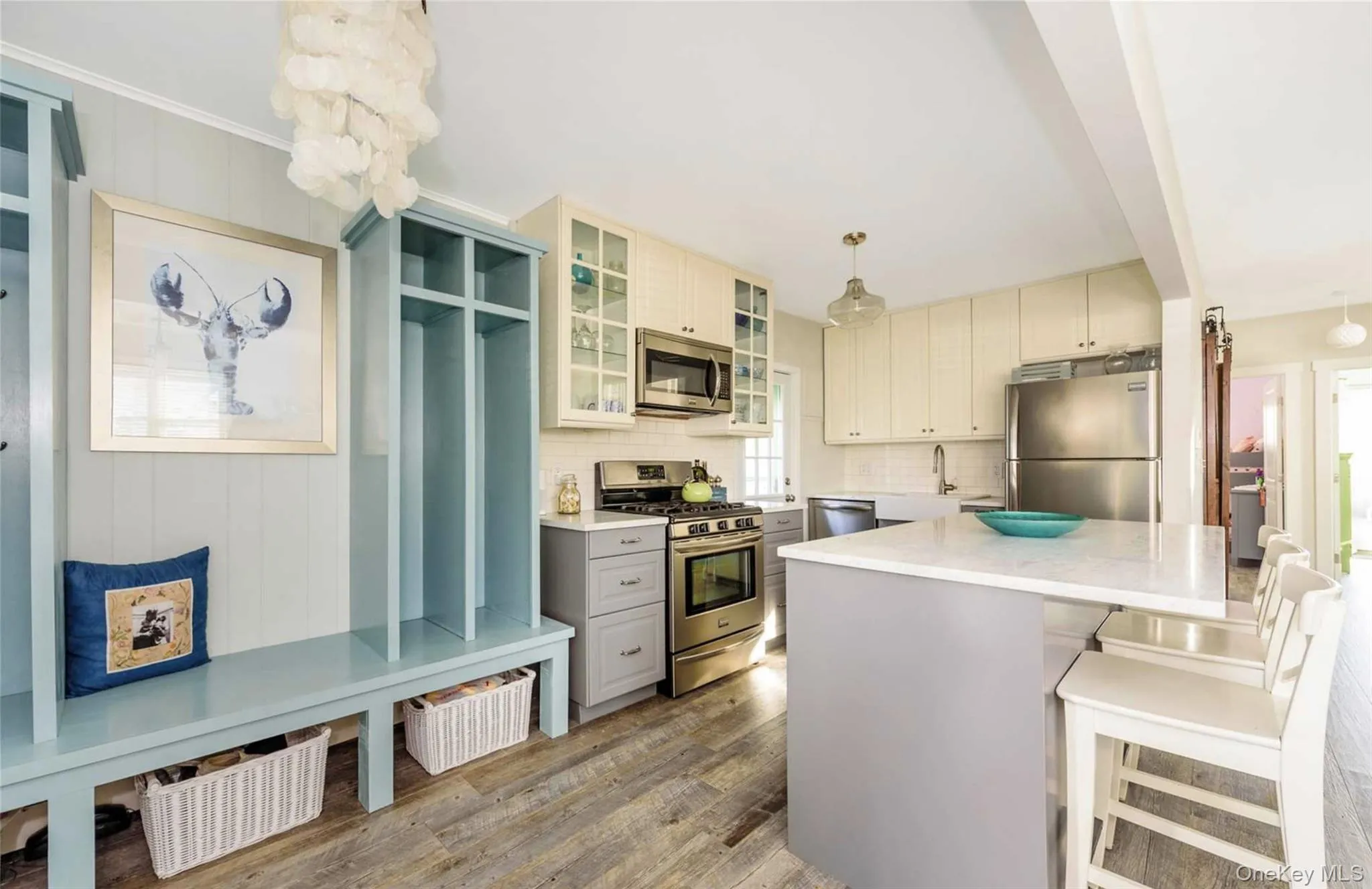 Kitchen with appliances with stainless steel finishes, tasteful backsplash, light hardwood / wood-style flooring, a center island, and hanging light fixtures Kitchen with appliances with stainless steel finishes, tasteful backsplash, light hardwood / wood-style flooring, a center island, and hanging light fixtures