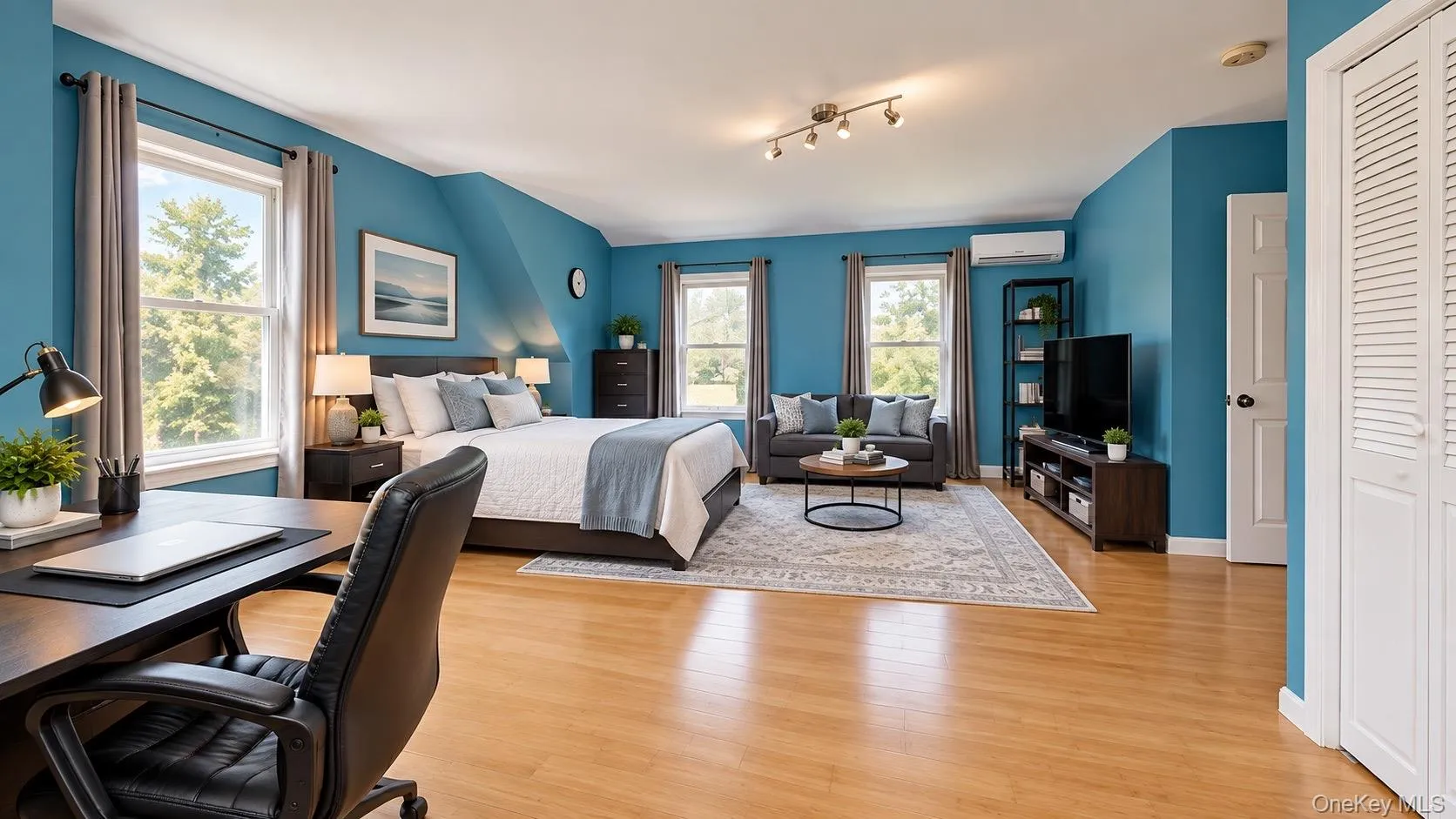 Warm wood-finish flooring with multiple windows, track lighting, and a white bi-fold closet door Warm wood-finish flooring with multiple windows, track lighting, and a white bi-fold closet door
