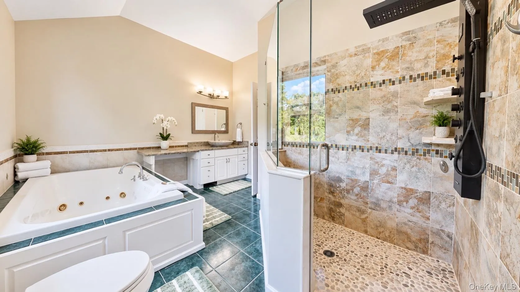 Soaking tub with green tile surround, walk-in shower with pebble floor, glass enclosure, vanity with basin sink, and tile flooring Soaking tub with green tile surround, walk-in shower with pebble floor, glass enclosure, vanity with basin sink, and tile flooring