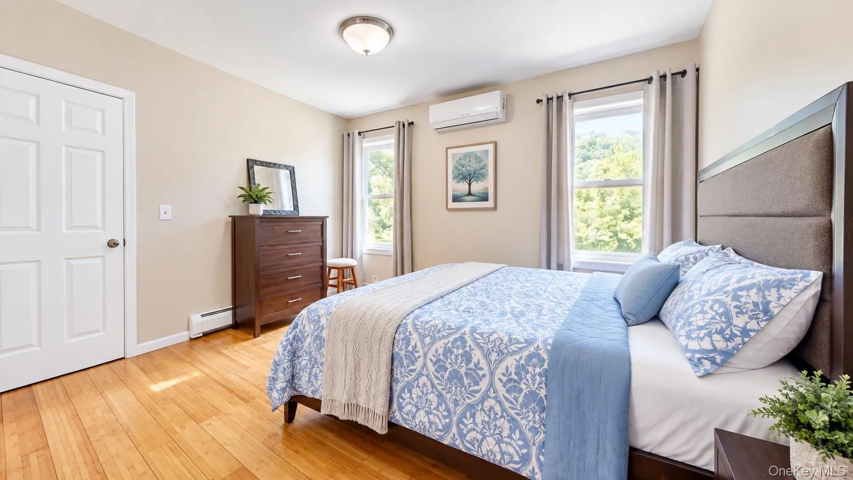 Hardwood flooring, neutral wall tones, modern ceiling light fixture, individual climate control unit, and window with exterior scenery Hardwood flooring, neutral wall tones, modern ceiling light fixture, individual climate control unit, and window with exterior scenery