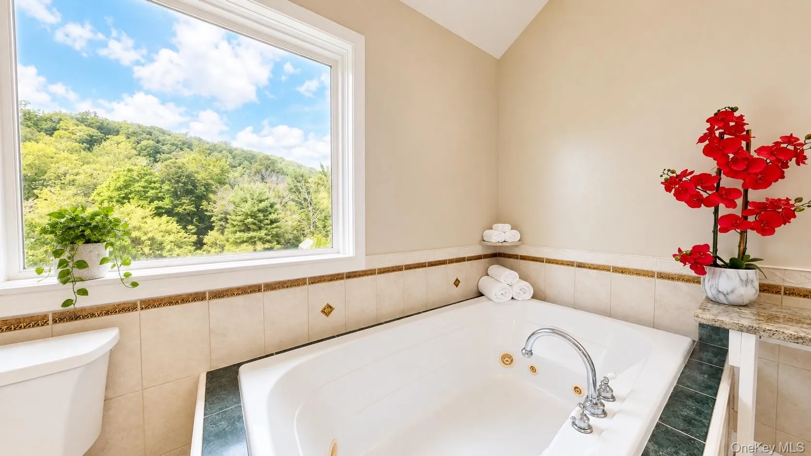 Built-in jetted tub with chrome fixtures, tiled surround, and a large window Built-in jetted tub with chrome fixtures, tiled surround, and a large window