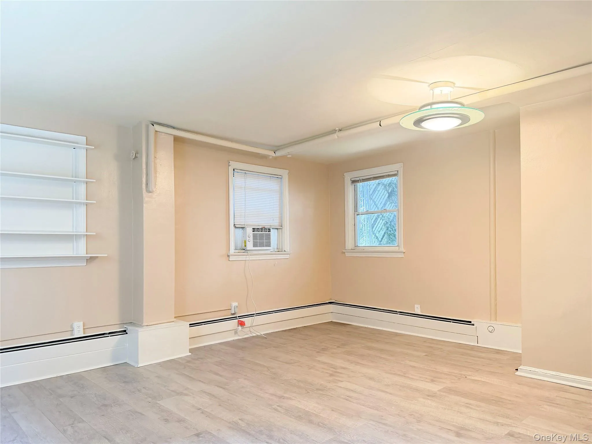 Engineered wood-finish flooring, two windows, and a flush-mount ceiling light fixture Engineered wood-finish flooring, two windows, and a flush-mount ceiling light fixture