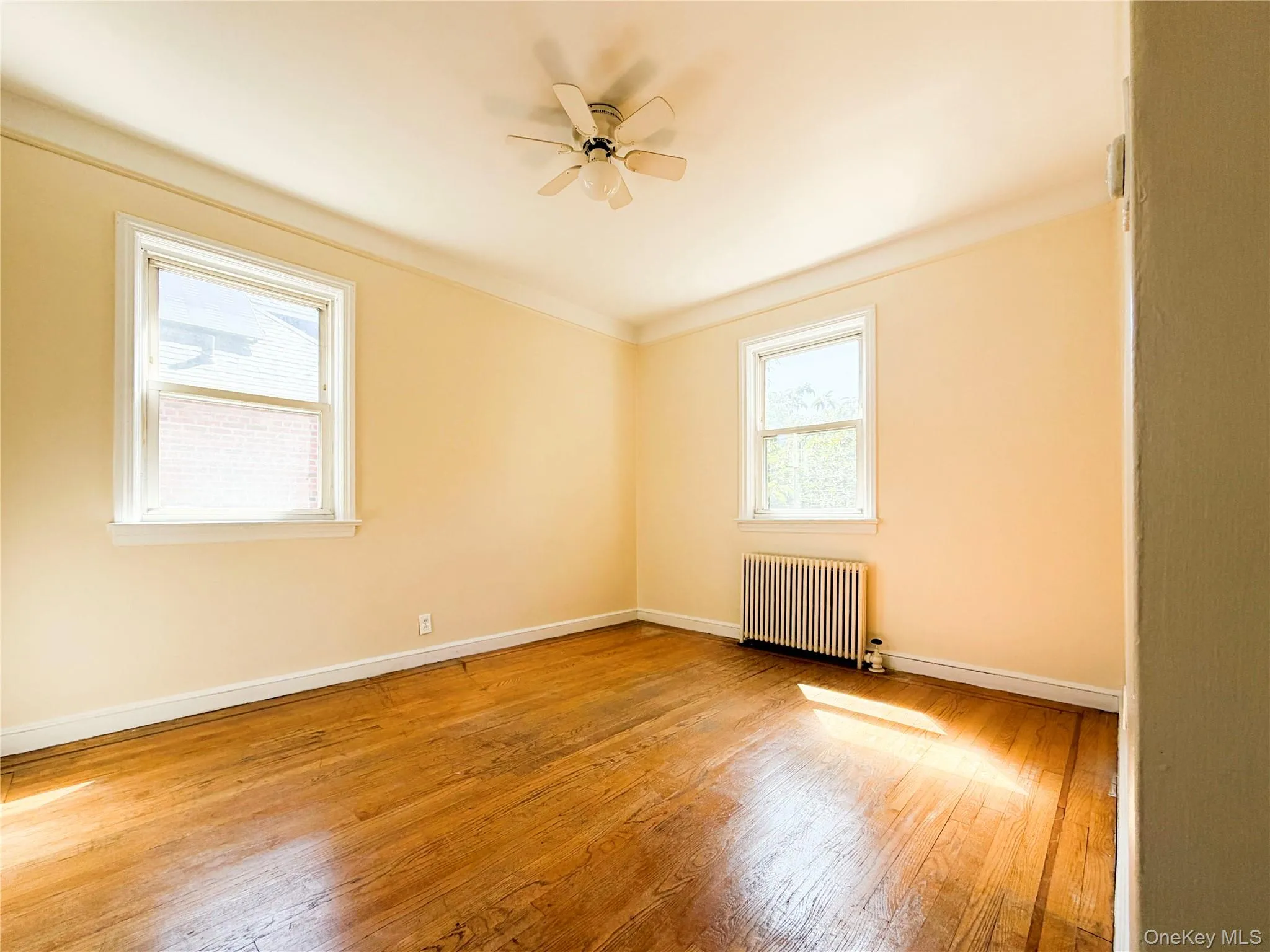 Hardwood flooring, two windows with white trim, a ceiling fan, and crown molding Hardwood flooring, two windows with white trim, a ceiling fan, and crown molding