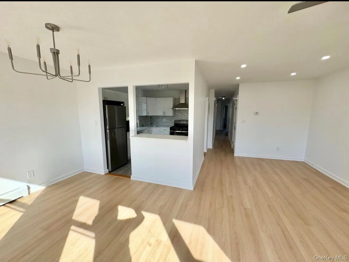 Open concept living area with wood-finish flooring, recessed lighting, and a modern chandelier Open concept living area with wood-finish flooring, recessed lighting, and a modern chandelier