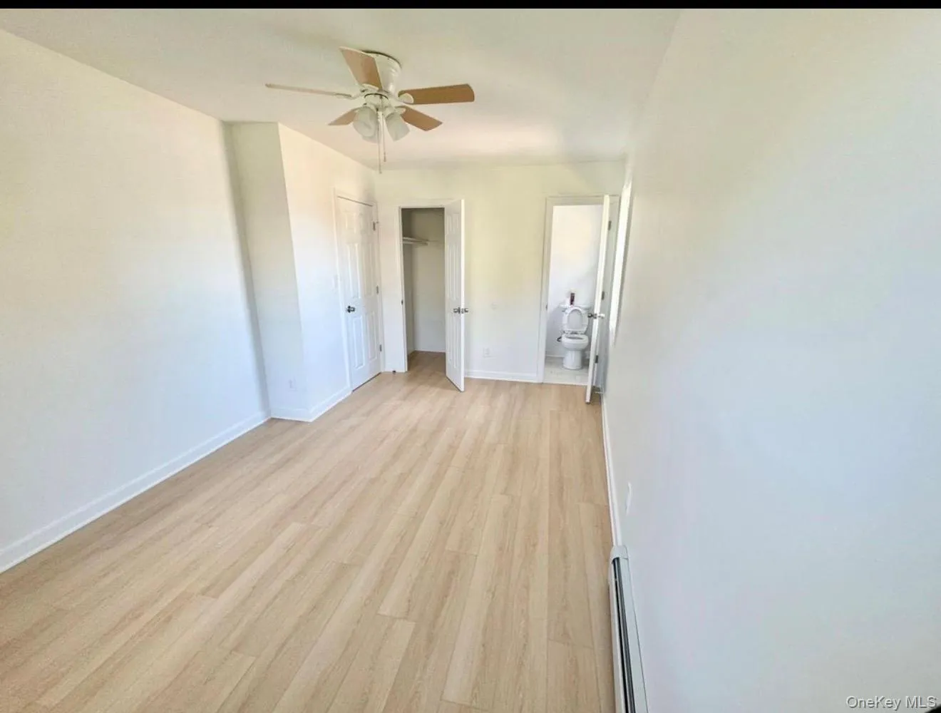 Spacious primary room featuring wood-finish flooring, a ceiling fan, and white walls Spacious primary room featuring wood-finish flooring, a ceiling fan, and white walls