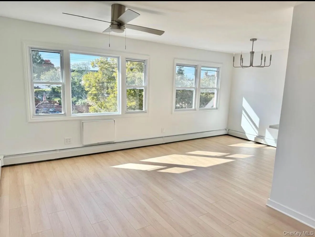Light wood-finish flooring, multiple pane windows, ceiling fan, and a contemporary chandelier Light wood-finish flooring, multiple pane windows, ceiling fan, and a contemporary chandelier