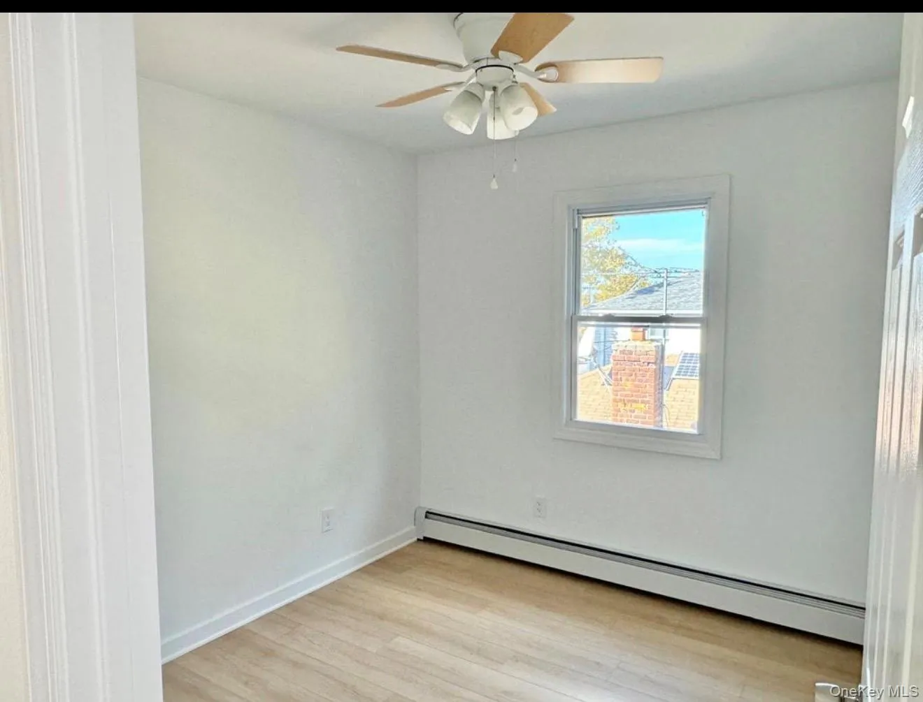 Wood-finish flooring, white painted walls, ceiling fan with light fixture, and a window with white trim Wood-finish flooring, white painted walls, ceiling fan with light fixture, and a window with white trim