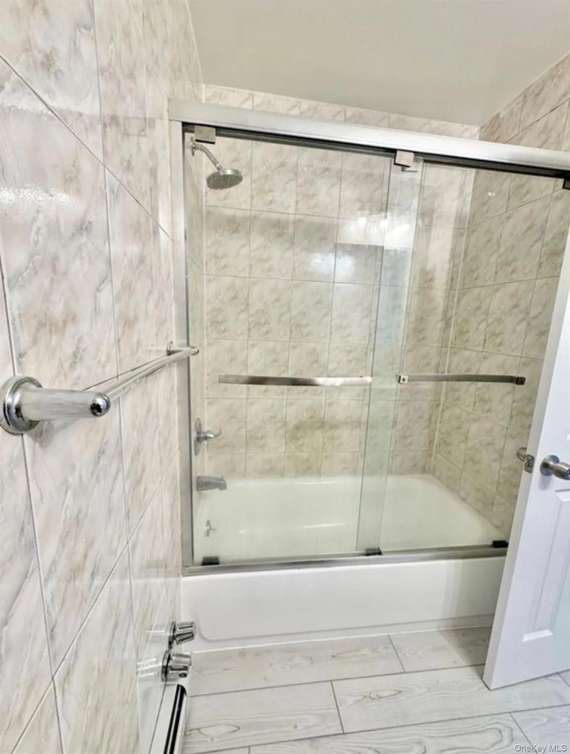 Bathtub with sliding glass enclosure, chrome fixtures, and tiled surround Bathtub with sliding glass enclosure, chrome fixtures, and tiled surround