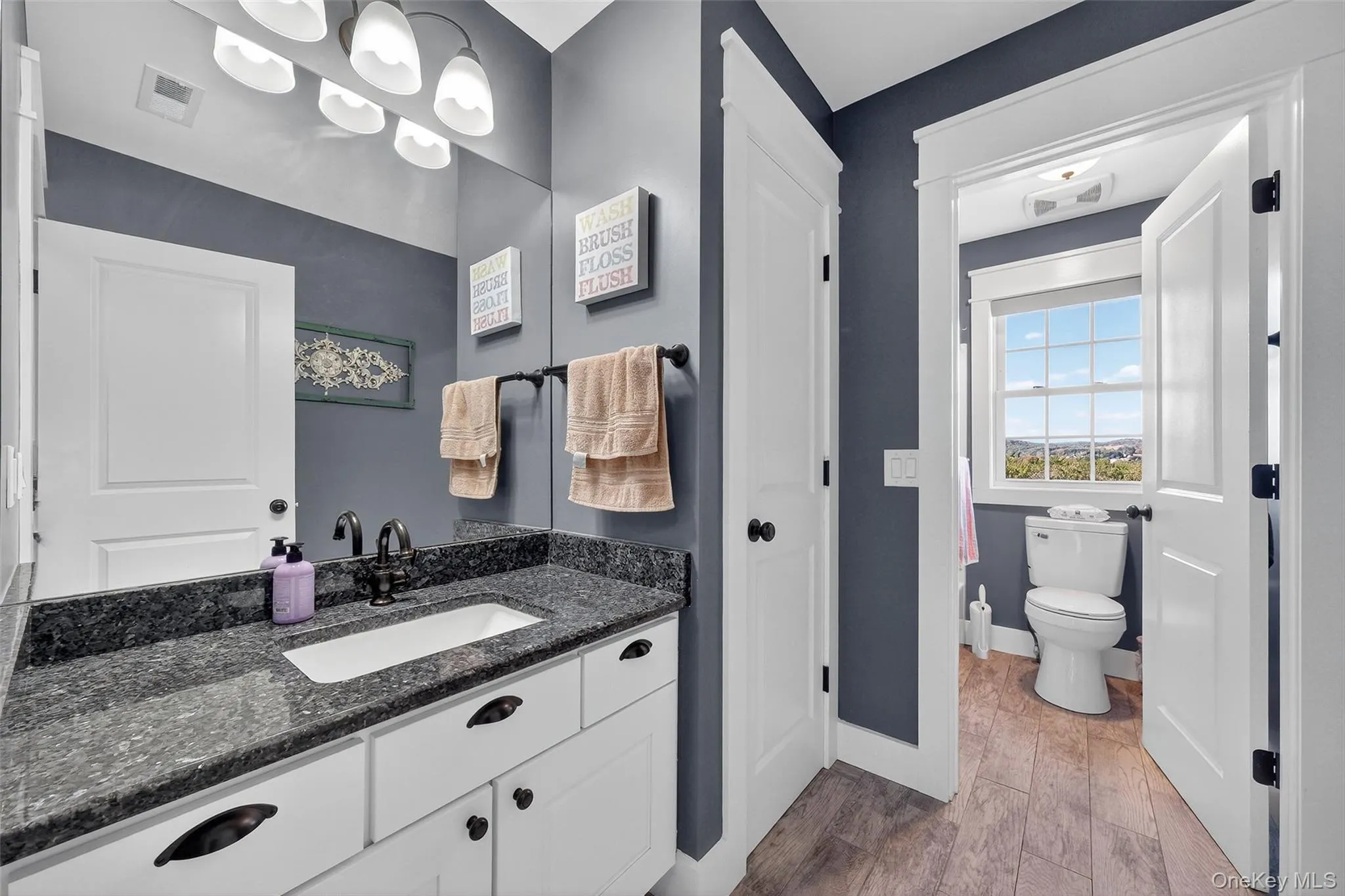 White vanity with dark stone-finish countertop, undermount sink, and black hardware White vanity with dark stone-finish countertop, undermount sink, and black hardware
