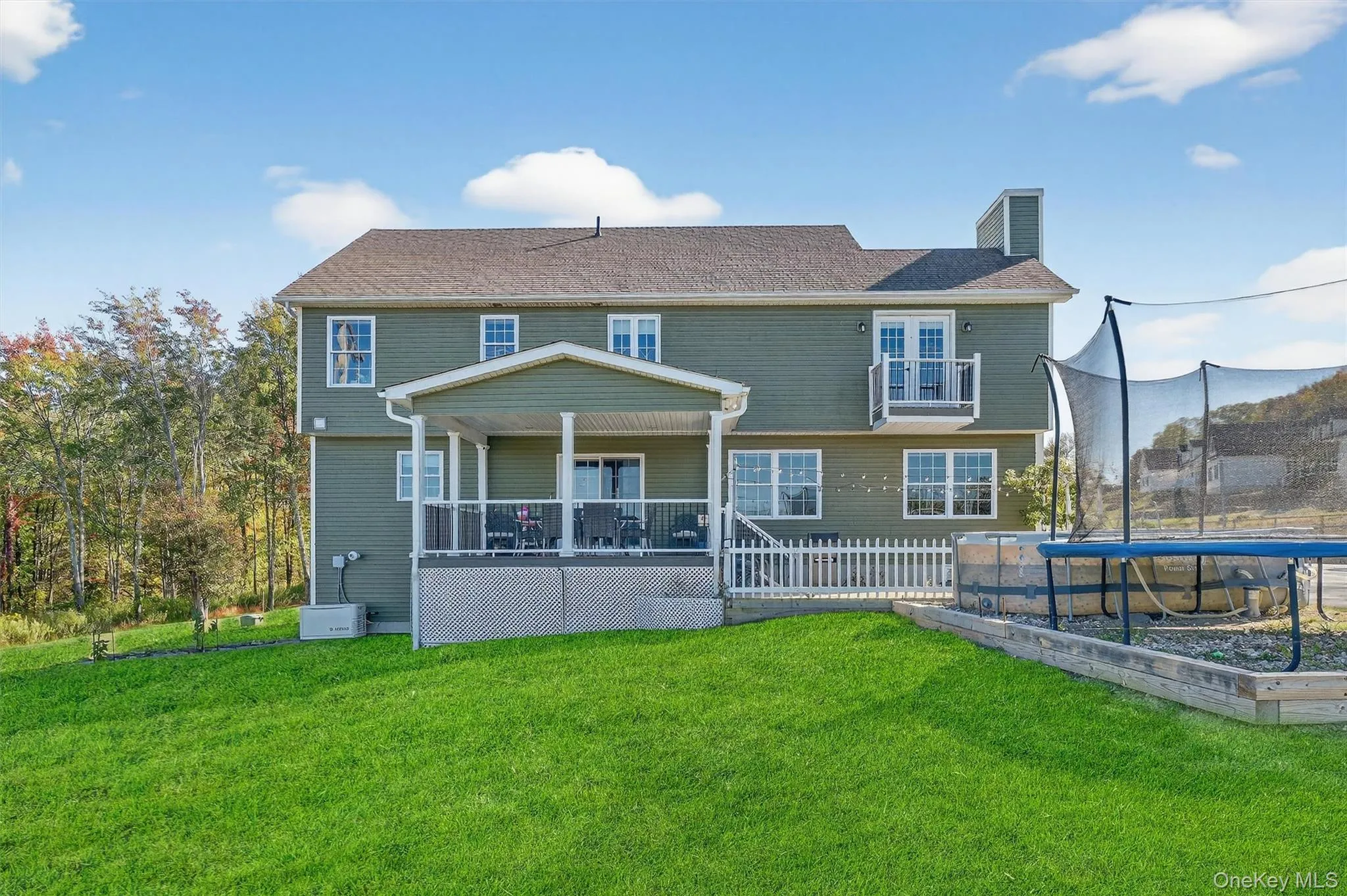 Expansive backyard with a covered deck, white picket fencing, and a second-story Juliet balcony Expansive backyard with a covered deck, white picket fencing, and a second-story Juliet balcony