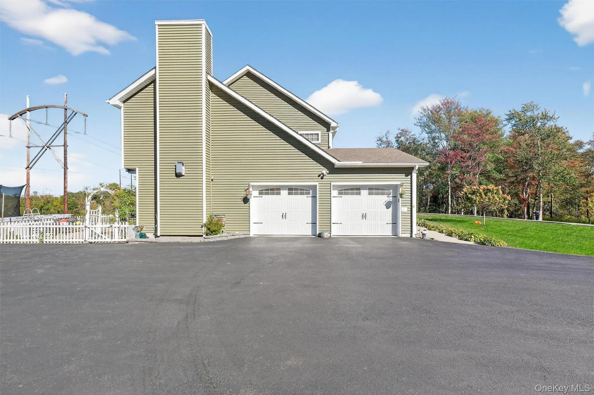 Green siding exterior with a prominent chimney and two white garage doors Green siding exterior with a prominent chimney and two white garage doors