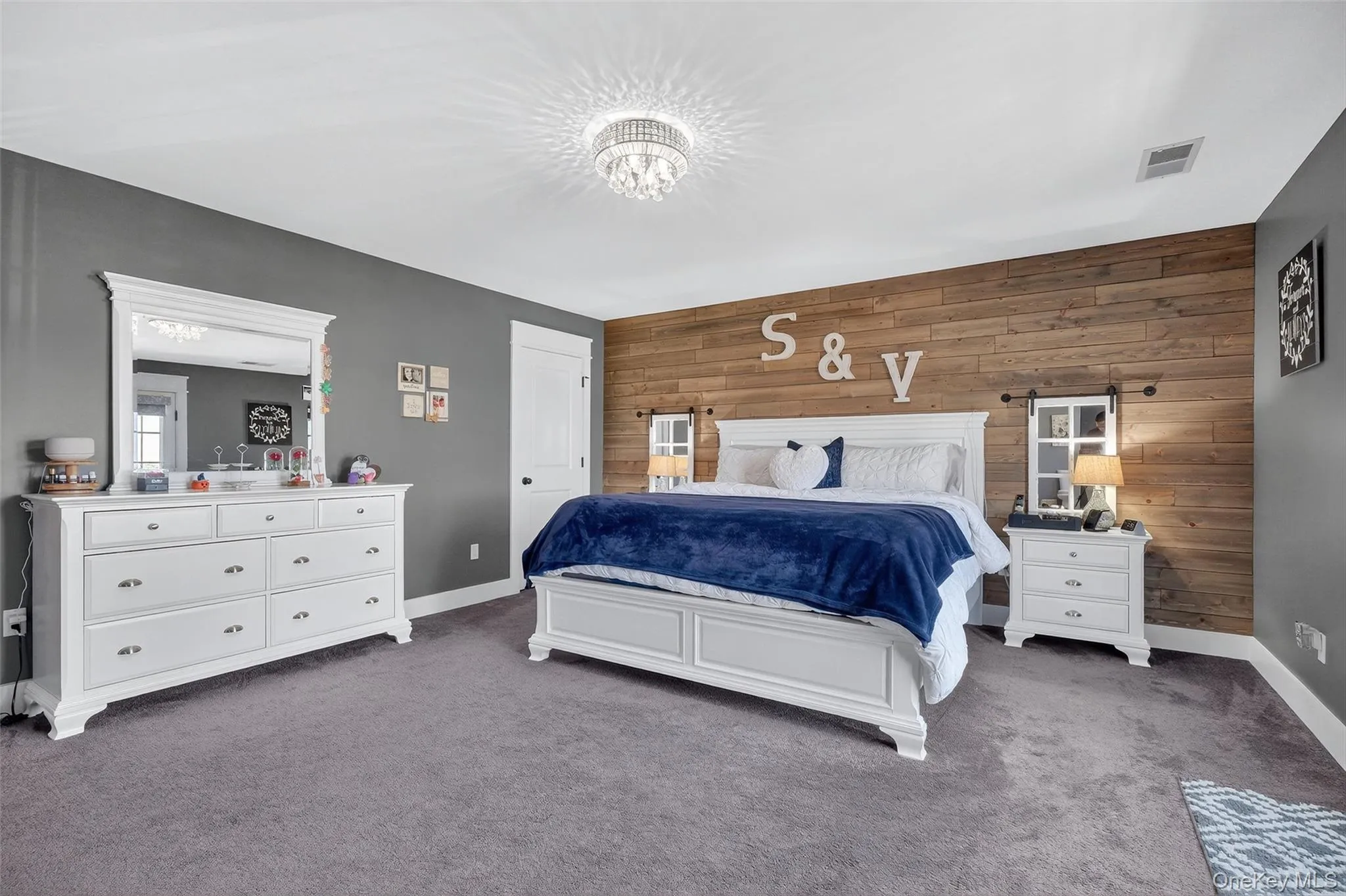 Wood-finish accent wall, ceiling-mounted chandelier, white trim, and gray wall paint Wood-finish accent wall, ceiling-mounted chandelier, white trim, and gray wall paint