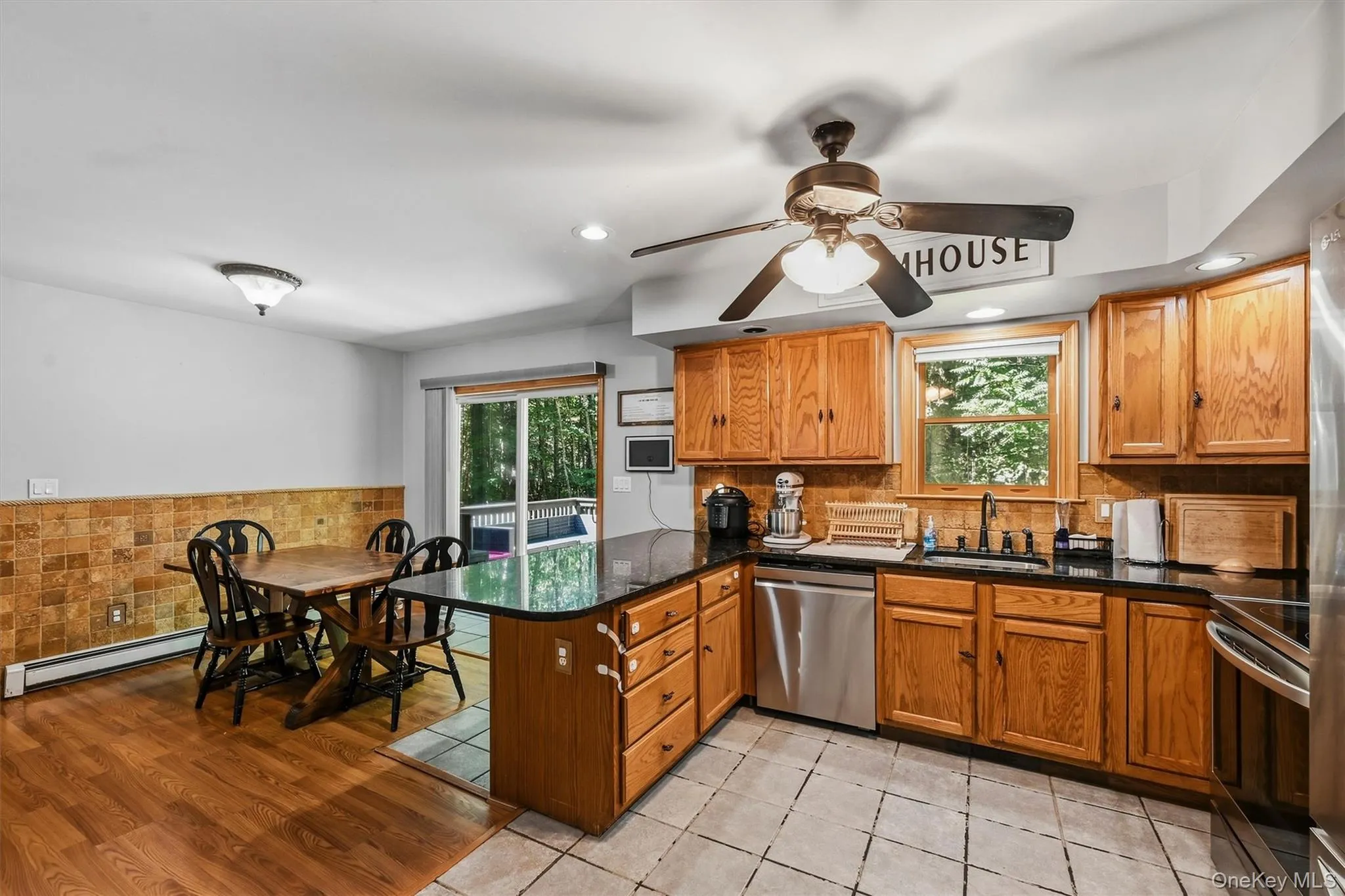 Wood-finish cabinetry with dark countertops, stainless steel appliances, tiled backsplash, and recessed lighting Wood-finish cabinetry with dark countertops, stainless steel appliances, tiled backsplash, and recessed lighting