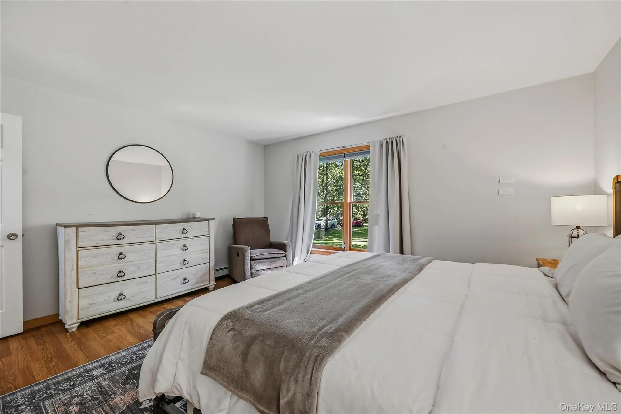 Hardwood flooring, light gray wall tones, white trim, and a window with tree scenery Hardwood flooring, light gray wall tones, white trim, and a window with tree scenery