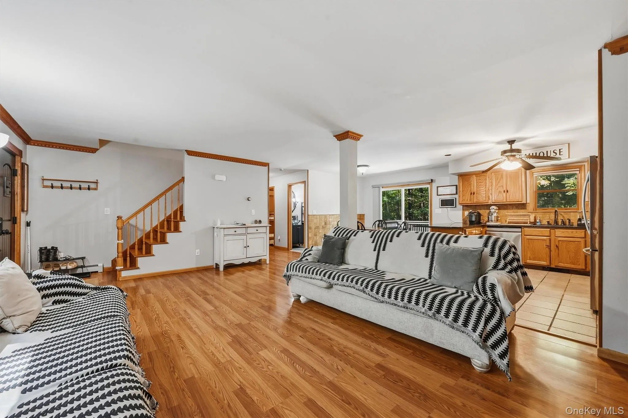 Hardwood-style flooring throughout, wood staircase with railing, wood cabinetry, and a ceiling fan with integrated lighting Hardwood-style flooring throughout, wood staircase with railing, wood cabinetry, and a ceiling fan with integrated lighting