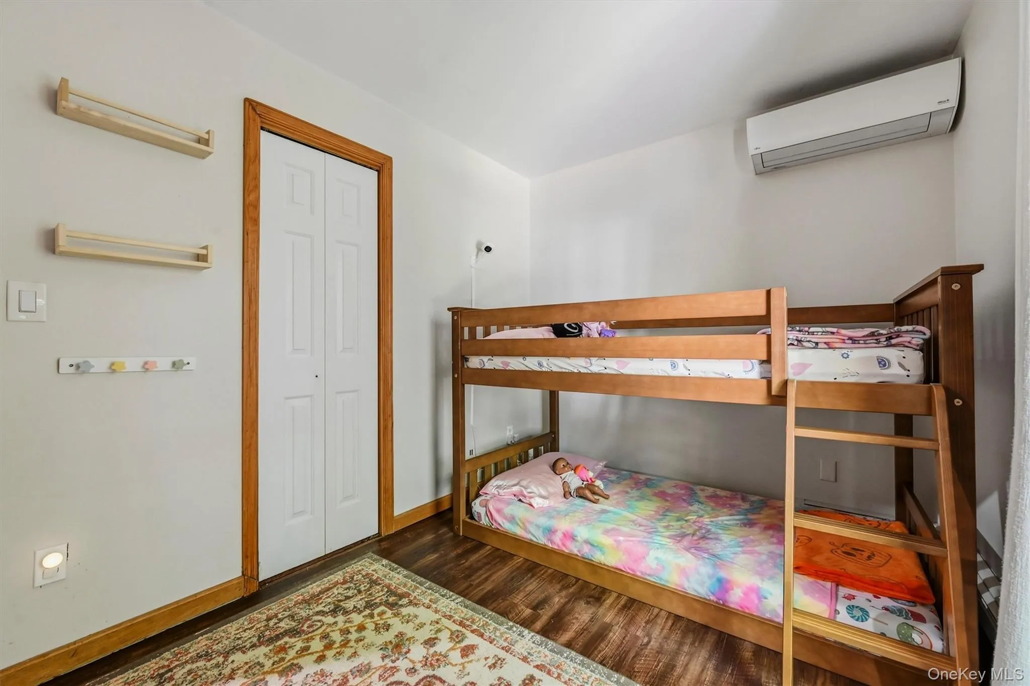 Wood-finish flooring with white walls, bi-fold closet doors, and wood trim accents Wood-finish flooring with white walls, bi-fold closet doors, and wood trim accents
