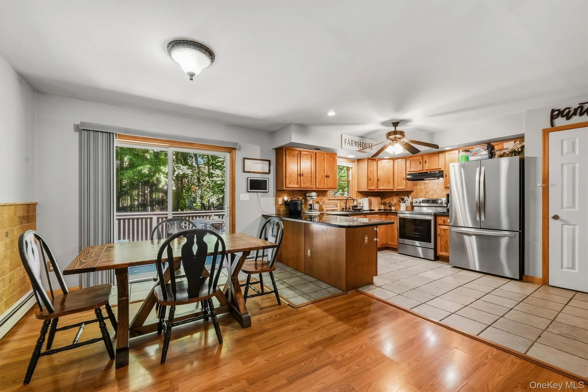 Kitchen featuring wood cabinetry, stainless steel appliances, a ceiling fan, and a tile floor Kitchen featuring wood cabinetry, stainless steel appliances, a ceiling fan, and a tile floor