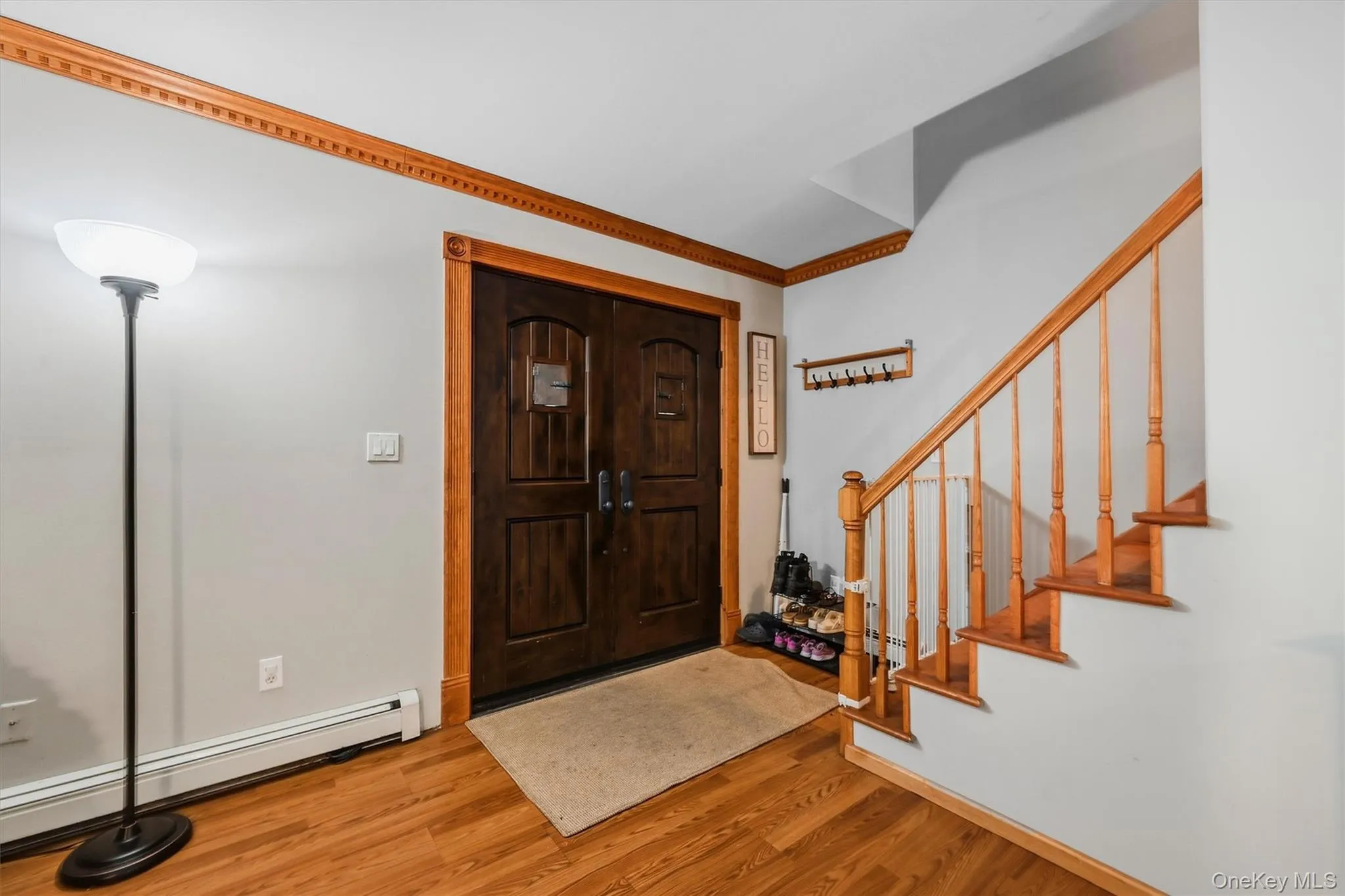 Double entry doors with decorative glass panels, wood-finish flooring, and a wood staircase with balusters Double entry doors with decorative glass panels, wood-finish flooring, and a wood staircase with balusters