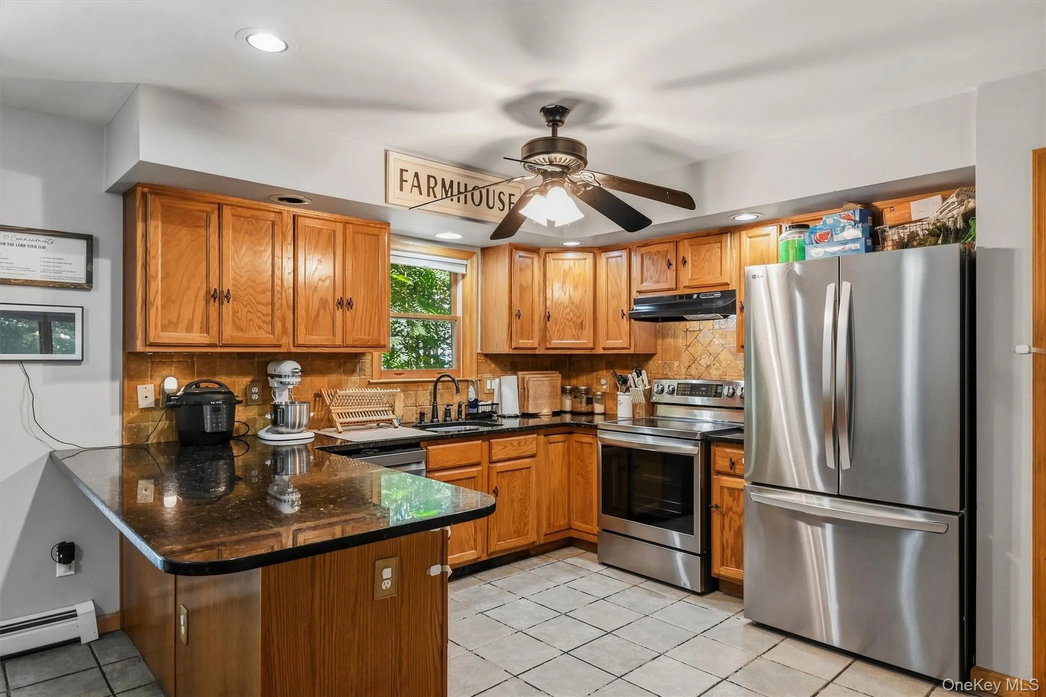 Kitchen featuring wood cabinetry, dark countertops, stainless steel appliances, a tiled backsplash, and recessed lighting Kitchen featuring wood cabinetry, dark countertops, stainless steel appliances, a tiled backsplash, and recessed lighting