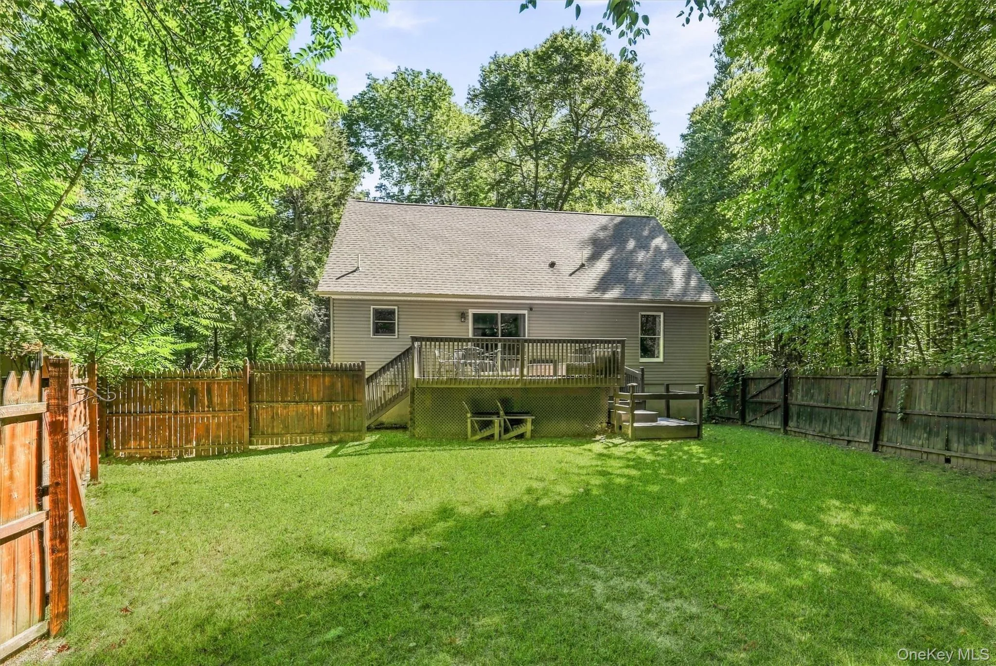 Expansive backyard featuring a manicured lawn, wood fencing, and a multi-level wood deck with stairs Expansive backyard featuring a manicured lawn, wood fencing, and a multi-level wood deck with stairs