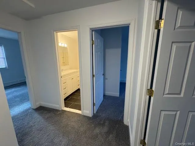 Hallway featuring dark carpet and doors to the bathroom and the three bedrooms on the second floor. Hallway featuring dark carpet and doors to the bathroom and the three bedrooms on the second floor.