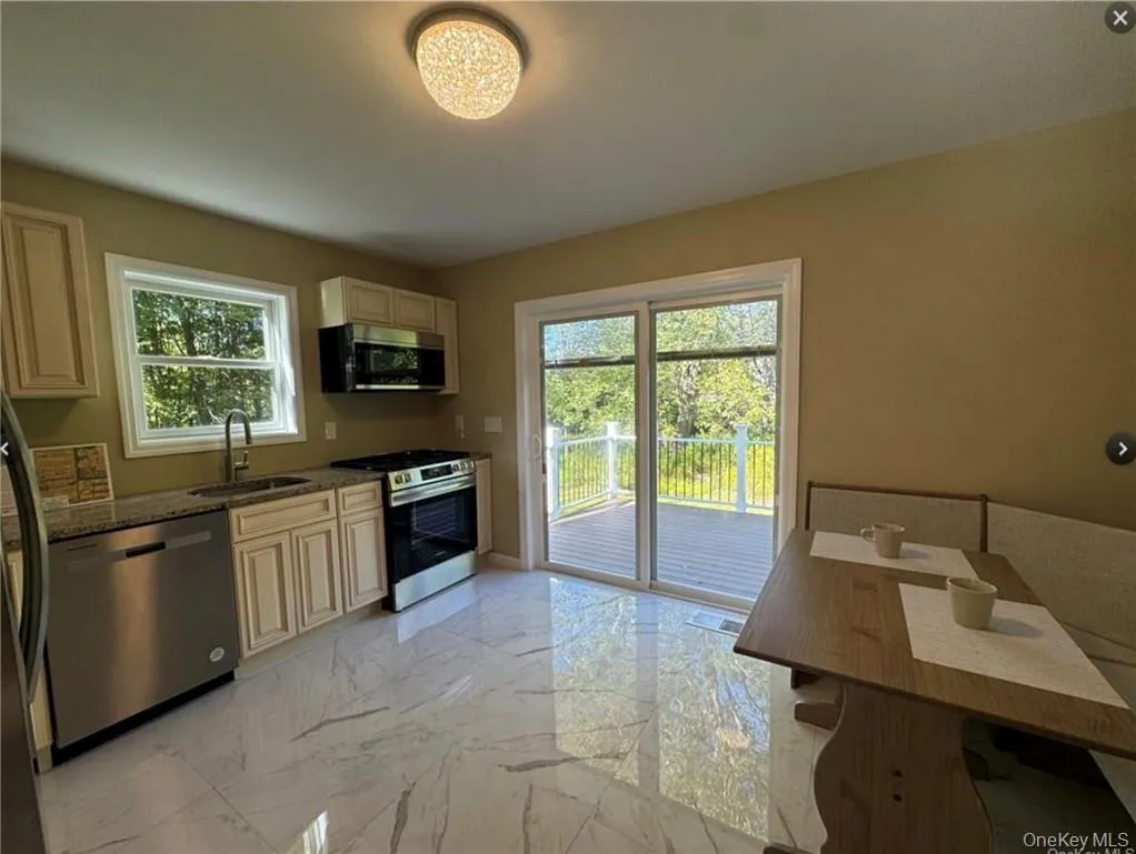 Kitchen featuring a wealth of natural light, sink, stainless steel appliances, and dark stone counters Kitchen featuring a wealth of natural light, sink, stainless steel appliances, and dark stone counters