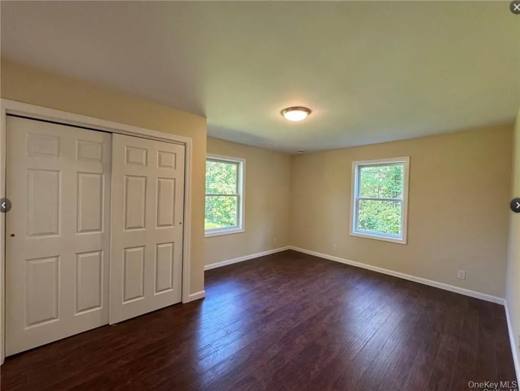 Unfurnished bedroom with dark hardwood / wood-style floors and a closet Unfurnished bedroom with dark hardwood / wood-style floors and a closet