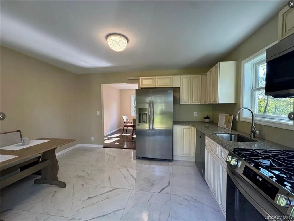 Kitchen with stainless steel appliances, light stone countertops, sink, and cream cabinets Kitchen with stainless steel appliances, light stone countertops, sink, and cream cabinets