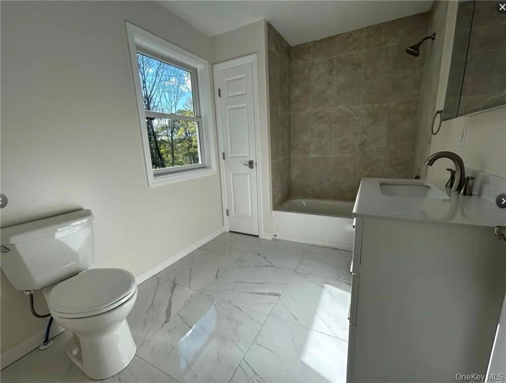 Full bathroom featuring vanity, tiled shower / bath combo, and toilet Full bathroom featuring vanity, tiled shower / bath combo, and toilet