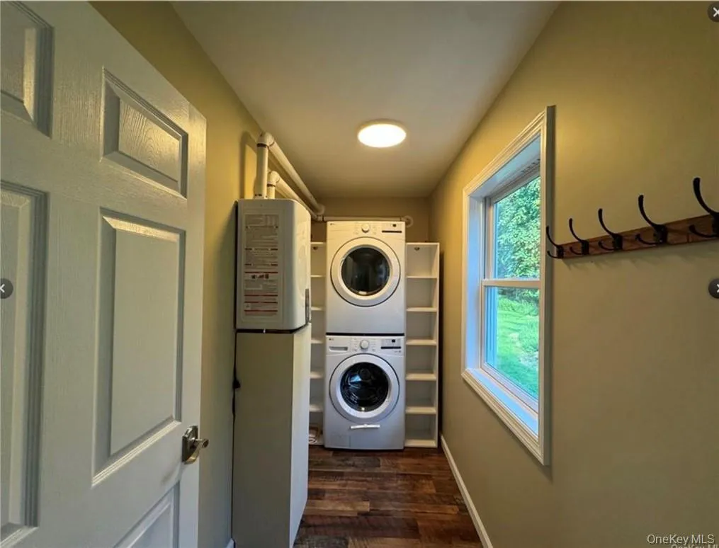 Laundry room featuring stacked washer and dryer and dark hardwood / wood-style floors Laundry room featuring stacked washer and dryer and dark hardwood / wood-style floors