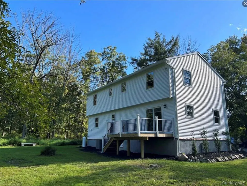 Rear view of house with a wooden deck and a yard Rear view of house with a wooden deck and a yard