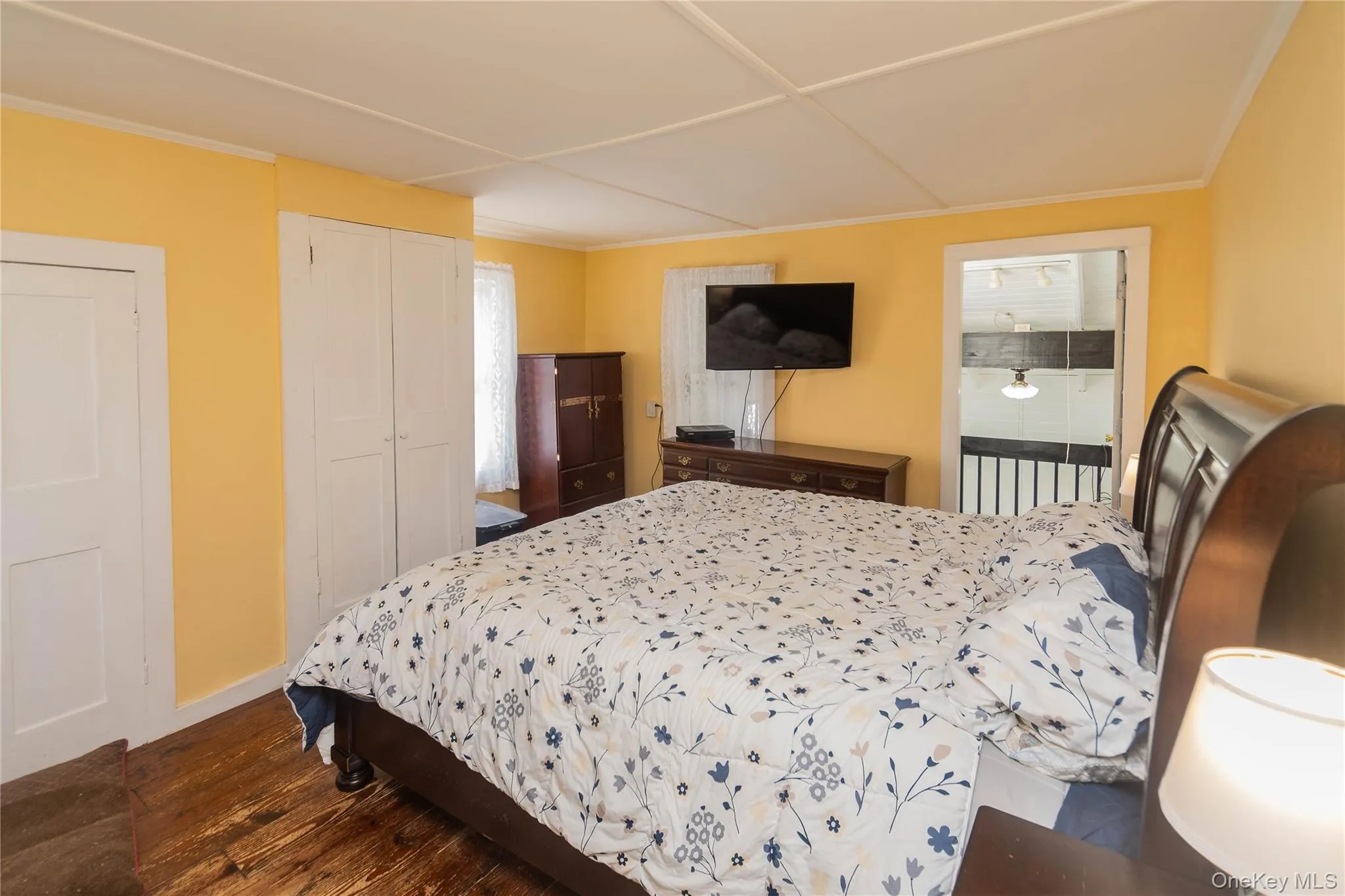 Bedroom with dark wood-style flooring, a closet, and crown molding Bedroom with dark wood-style flooring, a closet, and crown molding