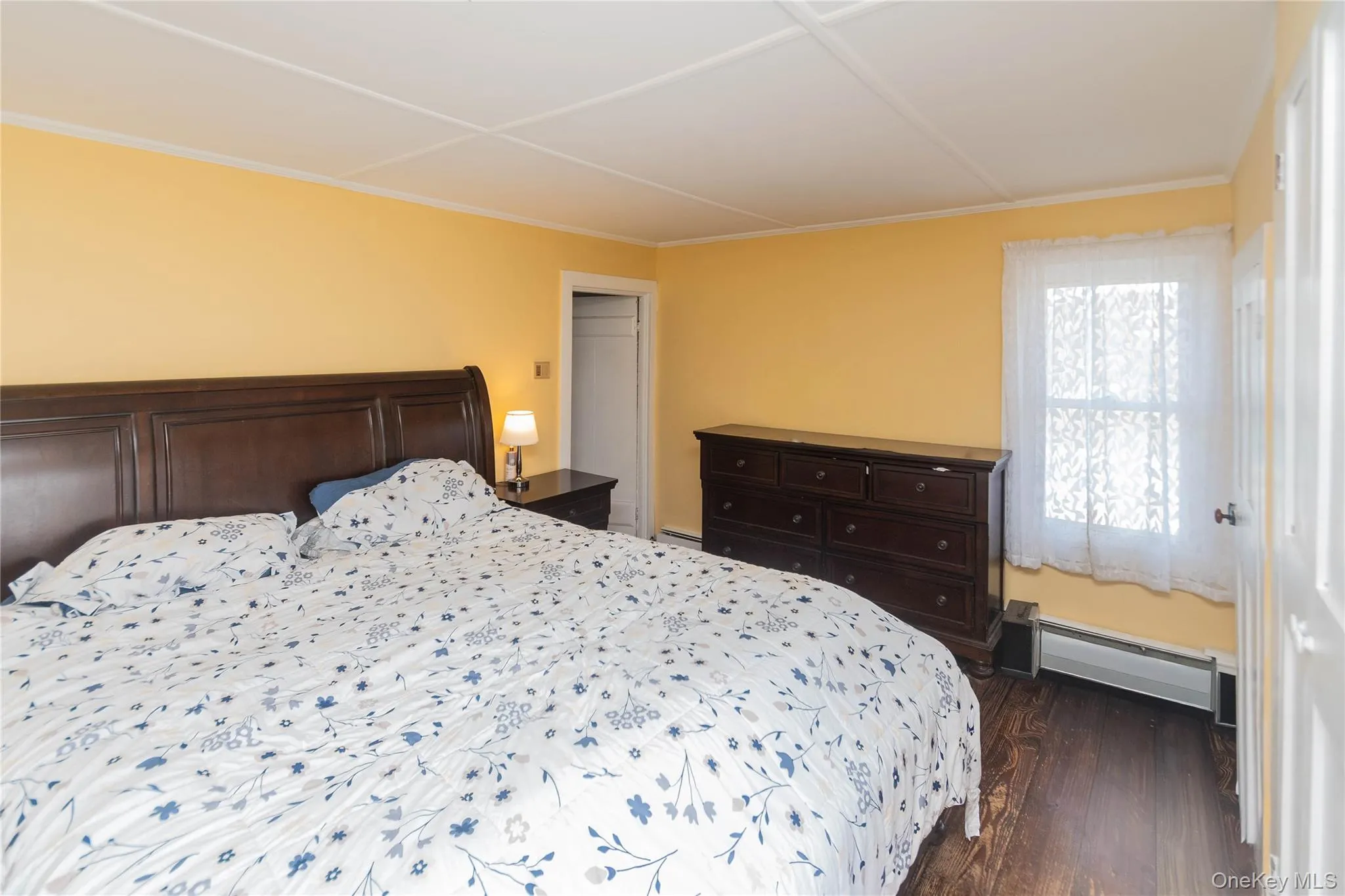 Bedroom featuring dark wood finished floors and a baseboard radiator Bedroom featuring dark wood finished floors and a baseboard radiator
