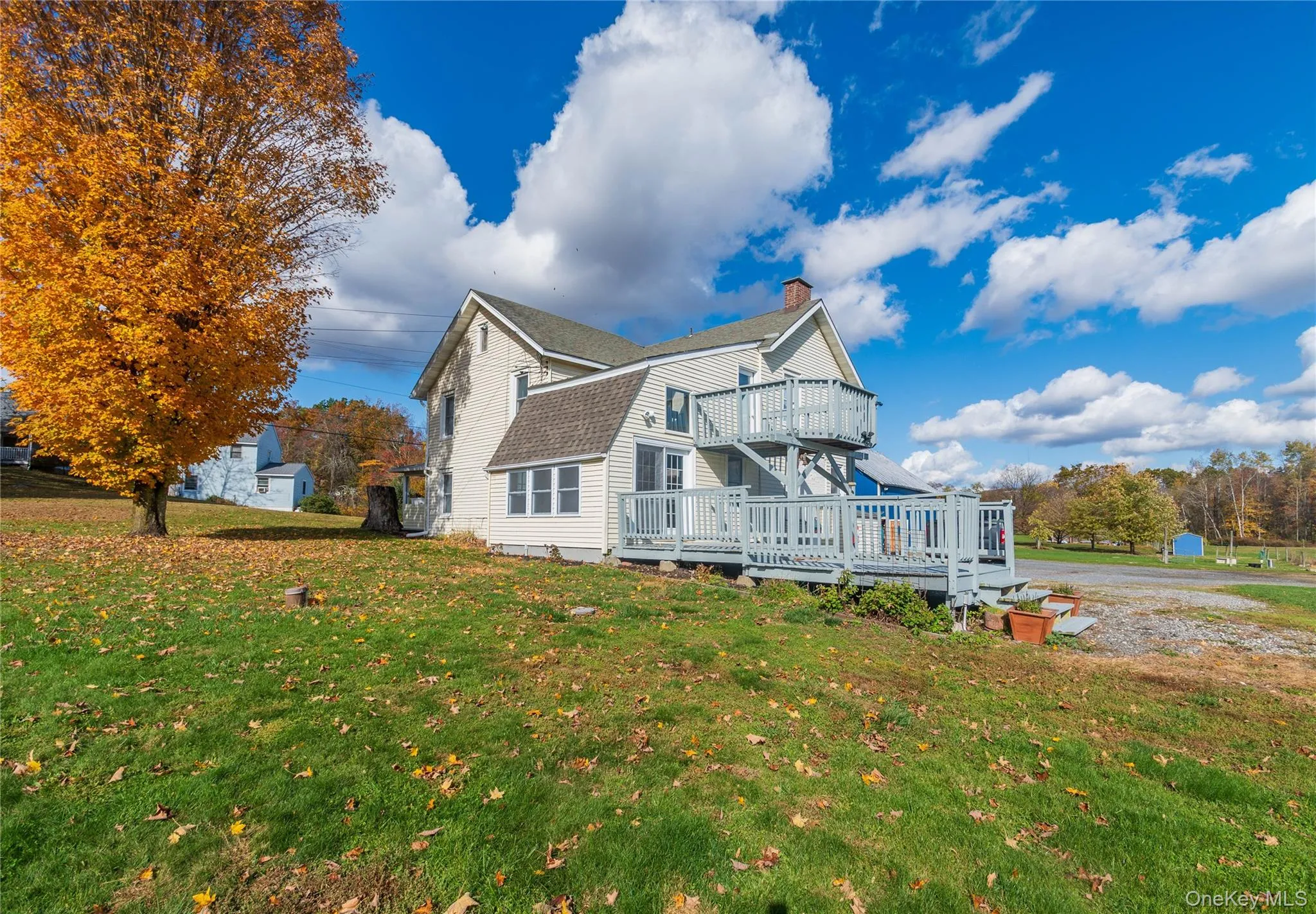 View of property exterior with a yard, a deck, a gambrel roof, a chimney, and a shingled roof View of property exterior with a yard, a deck, a gambrel roof, a chimney, and a shingled roof