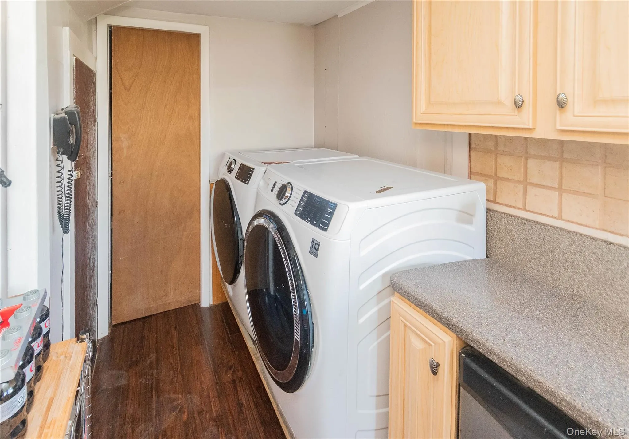 Laundry area with dark wood finished floors, washer and dryer, and cabinet space Laundry area with dark wood finished floors, washer and dryer, and cabinet space