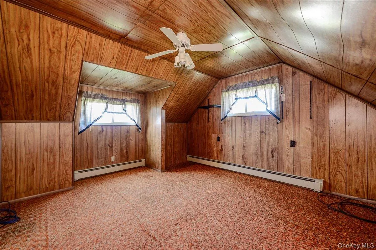 Wood-finish wall and ceiling paneling, sloped ceiling, and ceiling fan Wood-finish wall and ceiling paneling, sloped ceiling, and ceiling fan