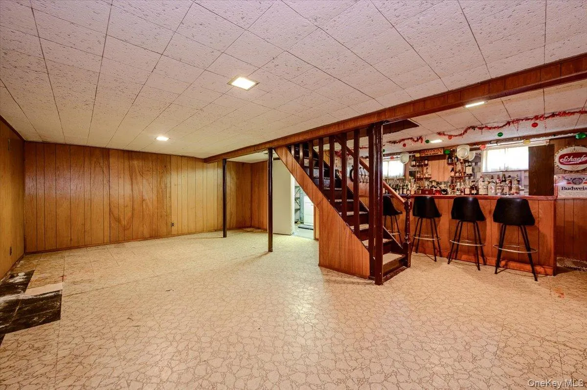 Wood paneling, a built-in bar, and a drop ceiling Wood paneling, a built-in bar, and a drop ceiling