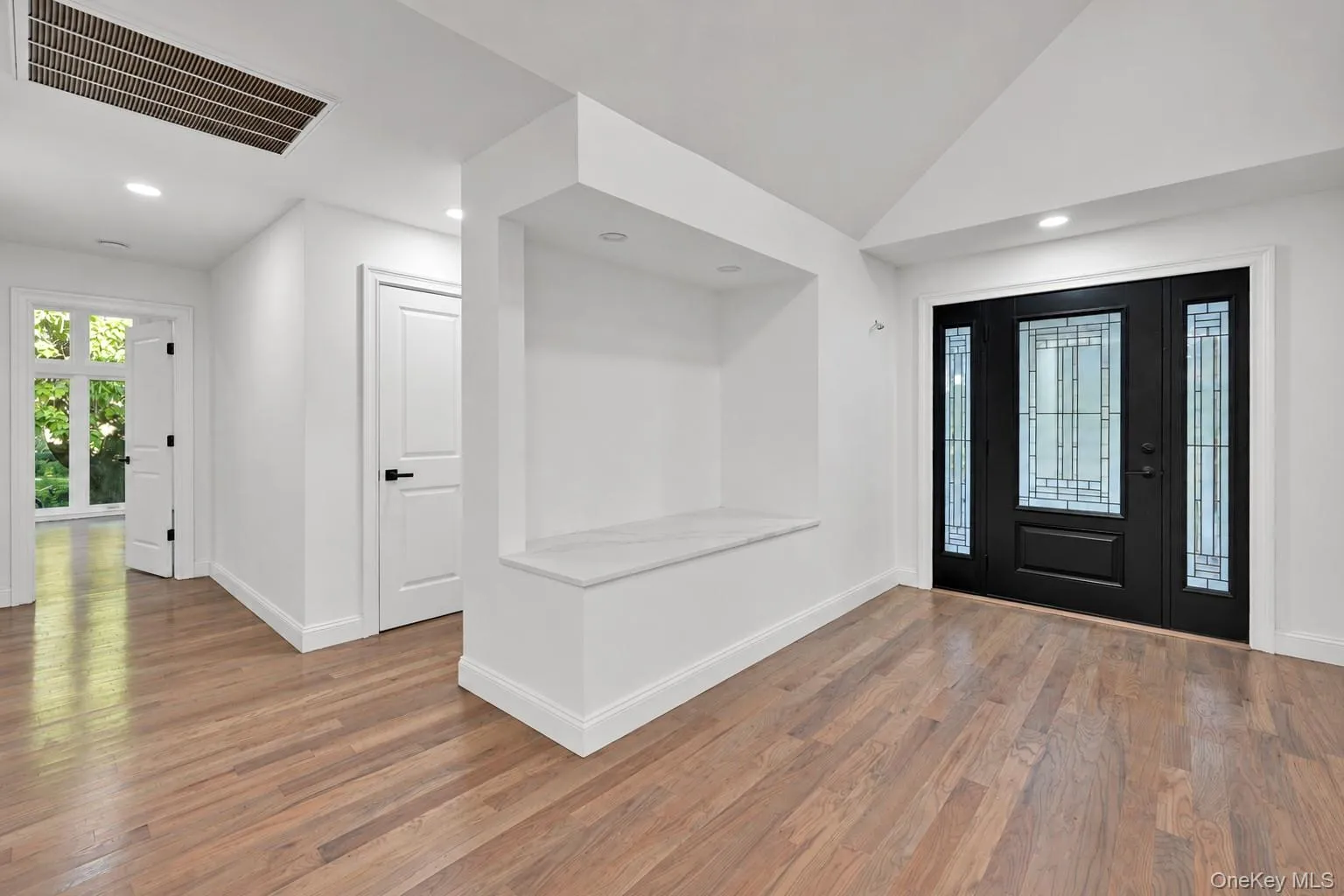 Wood-finish flooring throughout, recessed lighting, and a built-in wall niche with a light-colored surface Wood-finish flooring throughout, recessed lighting, and a built-in wall niche with a light-colored surface