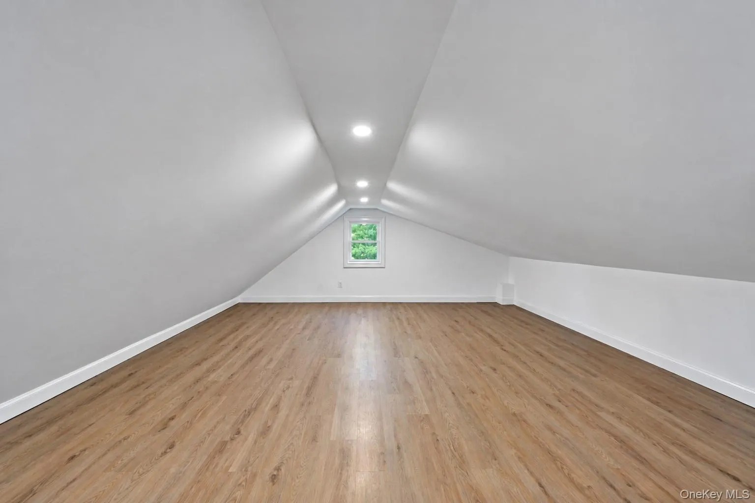 Wood-finish flooring, recessed lighting, white walls, white window frame, and sloped ceiling Wood-finish flooring, recessed lighting, white walls, white window frame, and sloped ceiling