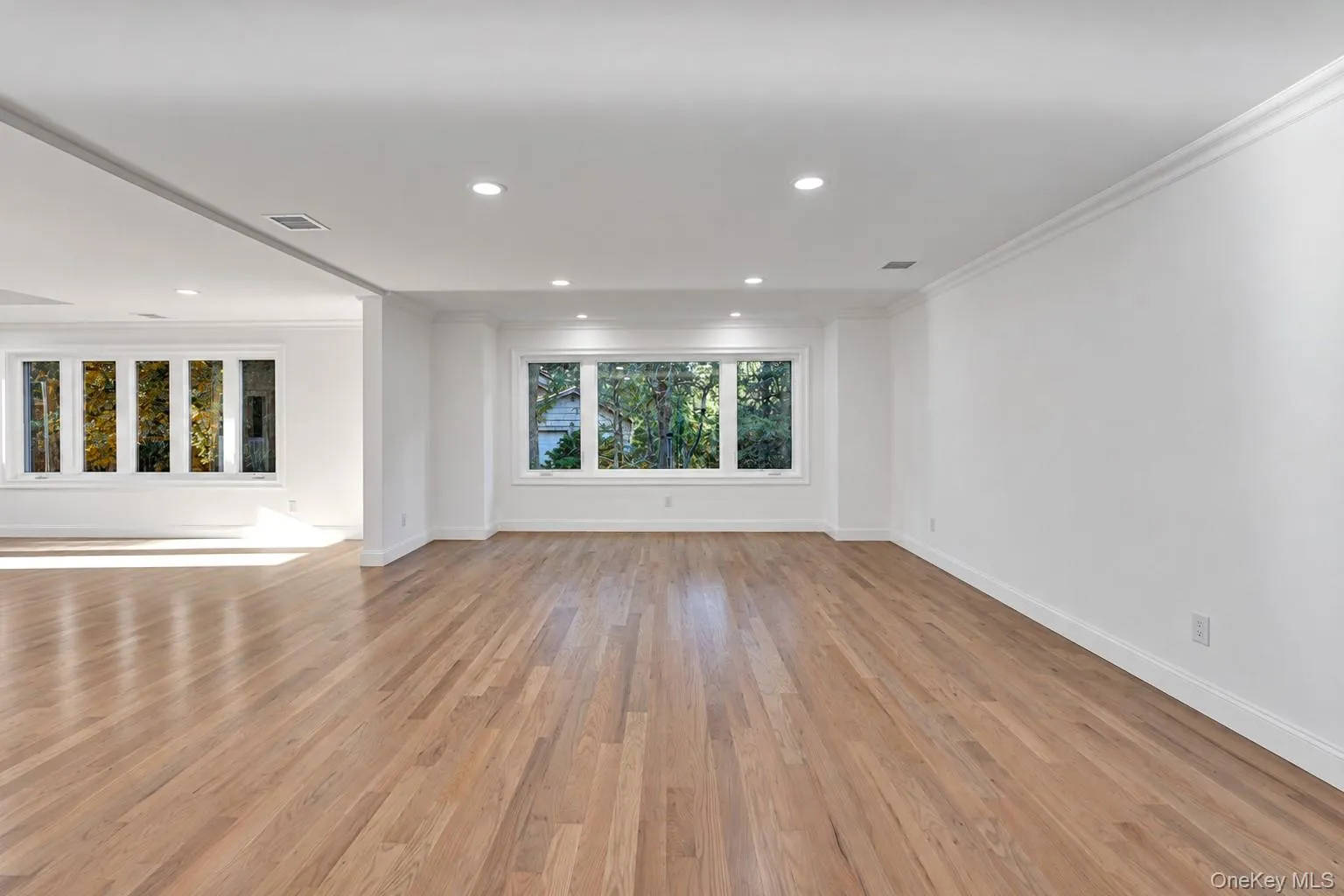 Hardwood flooring throughout, recessed lighting, crown molding, and multiple large windows with white trim Hardwood flooring throughout, recessed lighting, crown molding, and multiple large windows with white trim