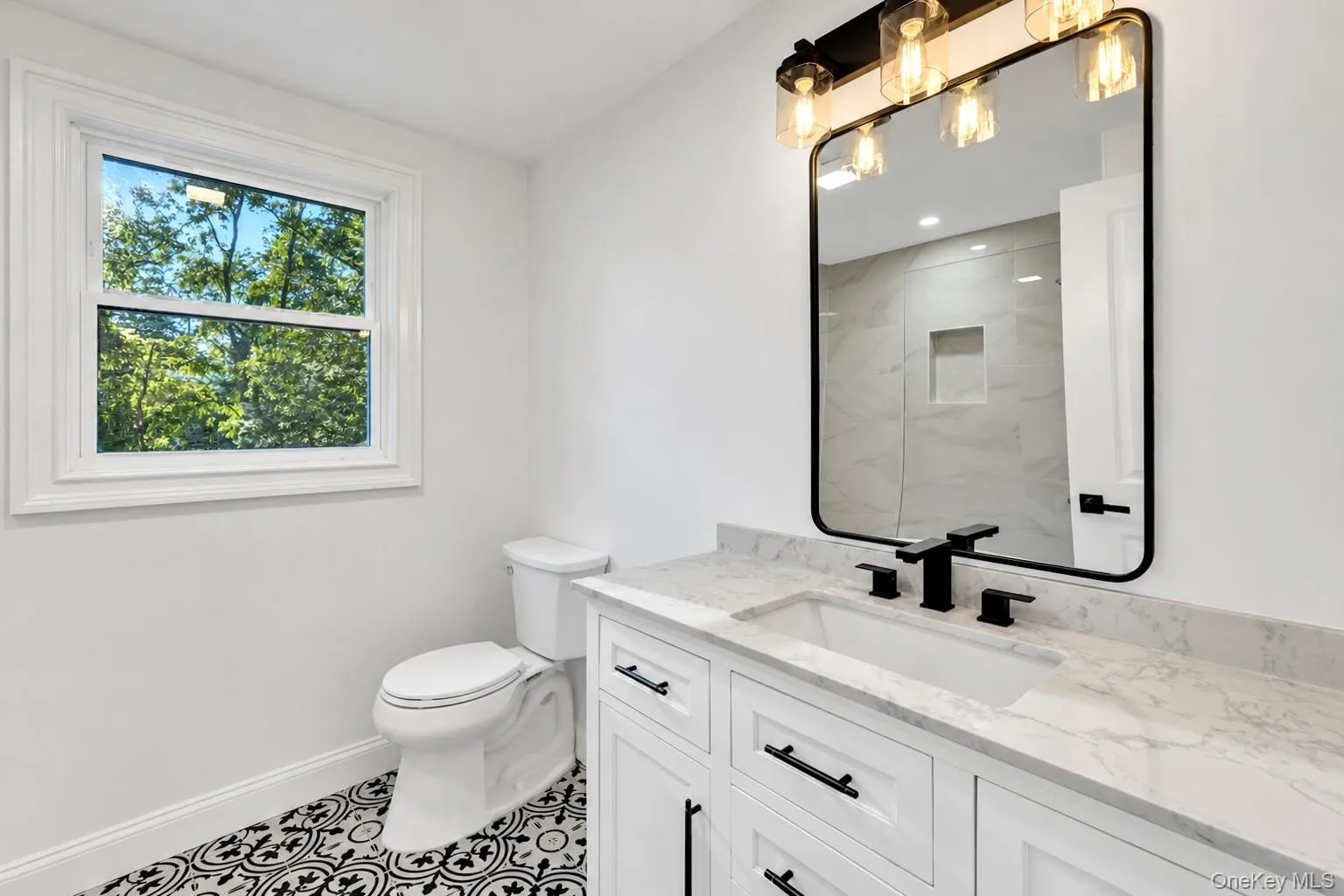 White shaker vanity with a light-toned countertop, undermount sink, and matte black fixtures White shaker vanity with a light-toned countertop, undermount sink, and matte black fixtures