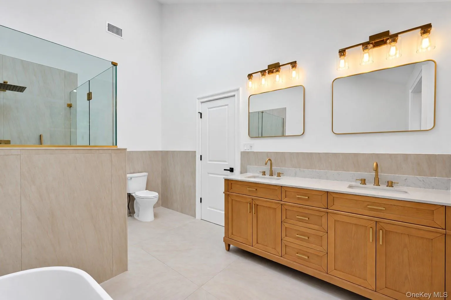 Double vanity with light wood cabinetry and gold-finish hardware Double vanity with light wood cabinetry and gold-finish hardware