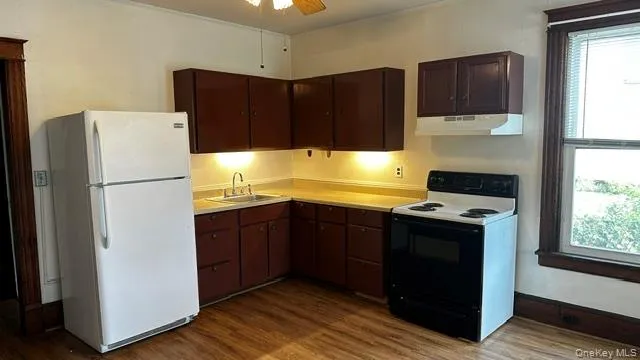 Kitchen featuring wood-finish flooring, corner upper and lower cabinetry. Kitchen featuring wood-finish flooring, corner upper and lower cabinetry.
